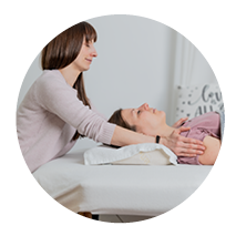 Therapeutin führt eine Behandlung an einer liegenden Patientin durch.