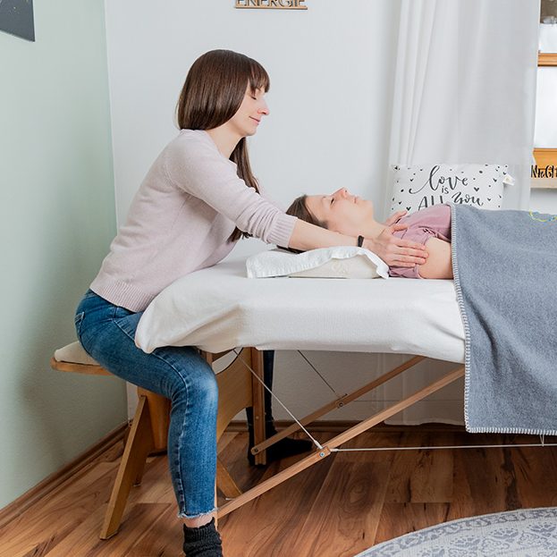Therapeutin Beate Kammerbauer gibt einer liegenden Person eine entspannende Behandlung.