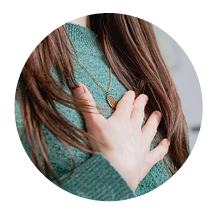 Beate Kammerbauer, die eine Kette trägt, mit langen Haaren und die Hand auf die Brust legt.